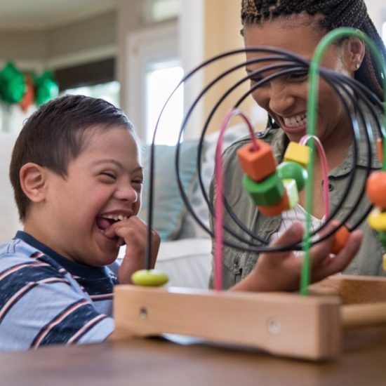 When the mid adult mom and her special needs son play in the living room, they laugh together.